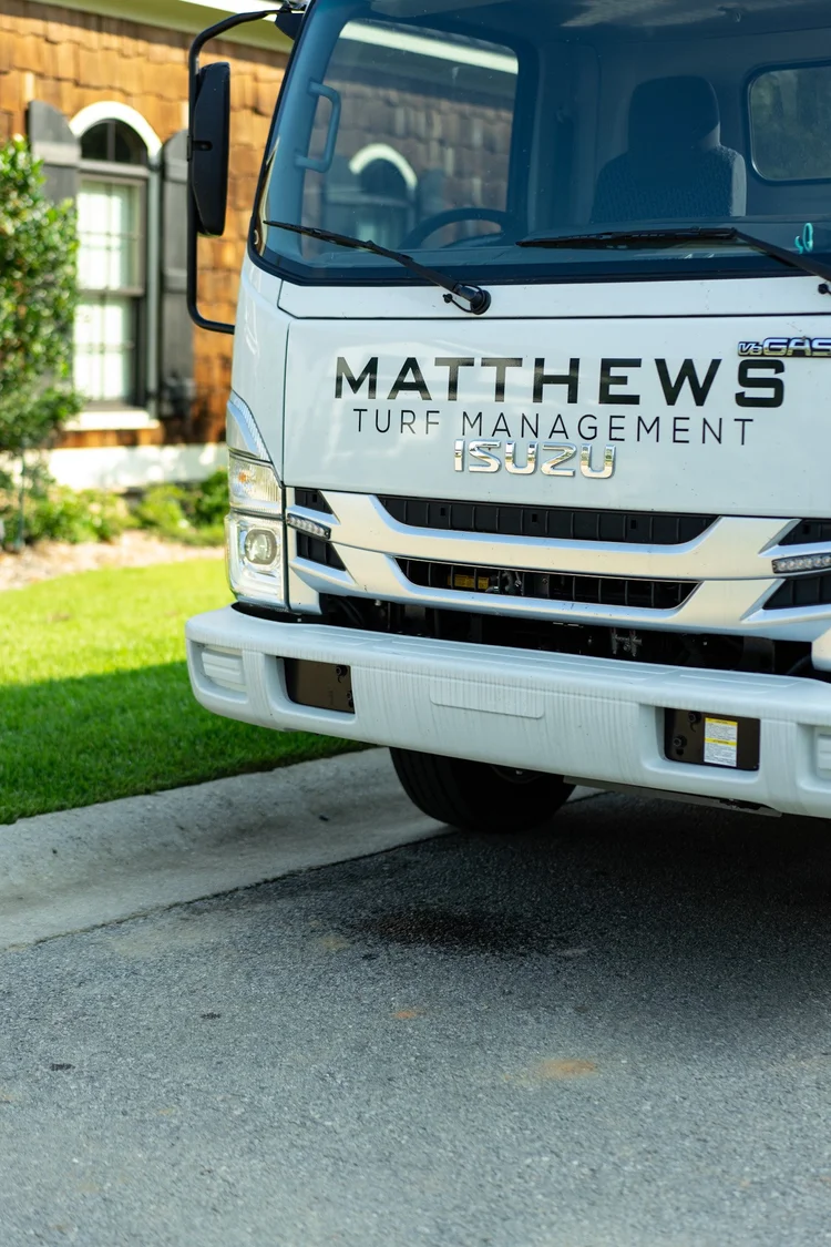 Matthews Turf Management Isuzu service truck parked on a residential driveway