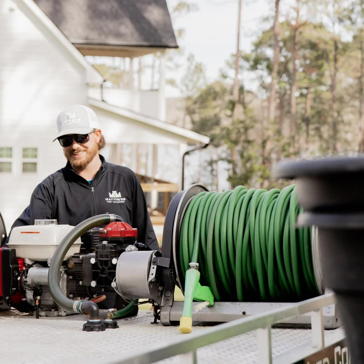 Matthews Turf Management employee with lawn care equipment and hose reel