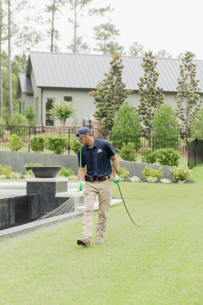 Technician treating a backyard lawn beside a pool