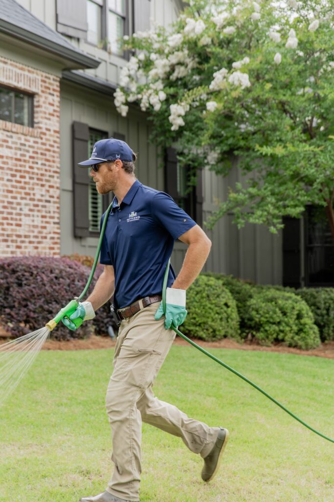 Technician applying lawn fertilization across a front yard