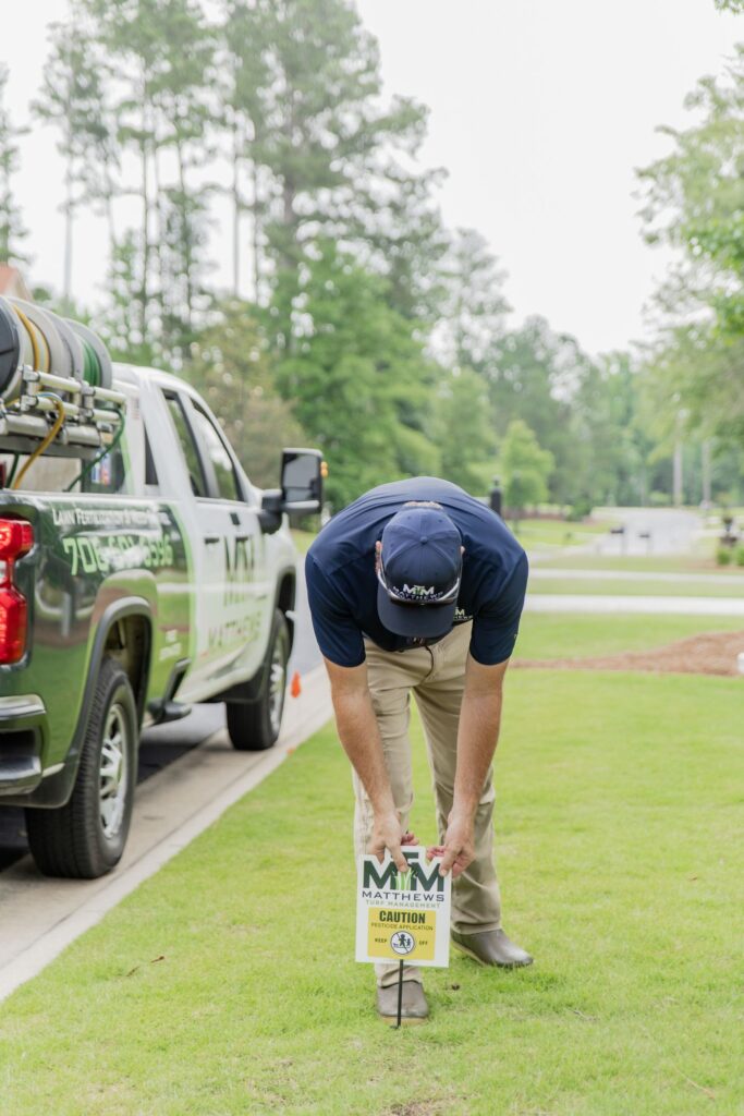 Technician placing a lawn application yard sign after treatment