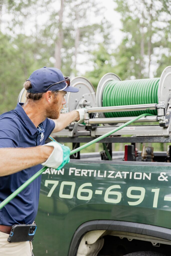 Matthews Turf Management technician pulling hose from the treatment truck reel